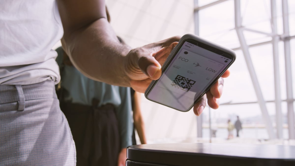 Pasajeros en sala de espera de un aeropuerto escaneando su pase de abordar digital, concepto de viaje