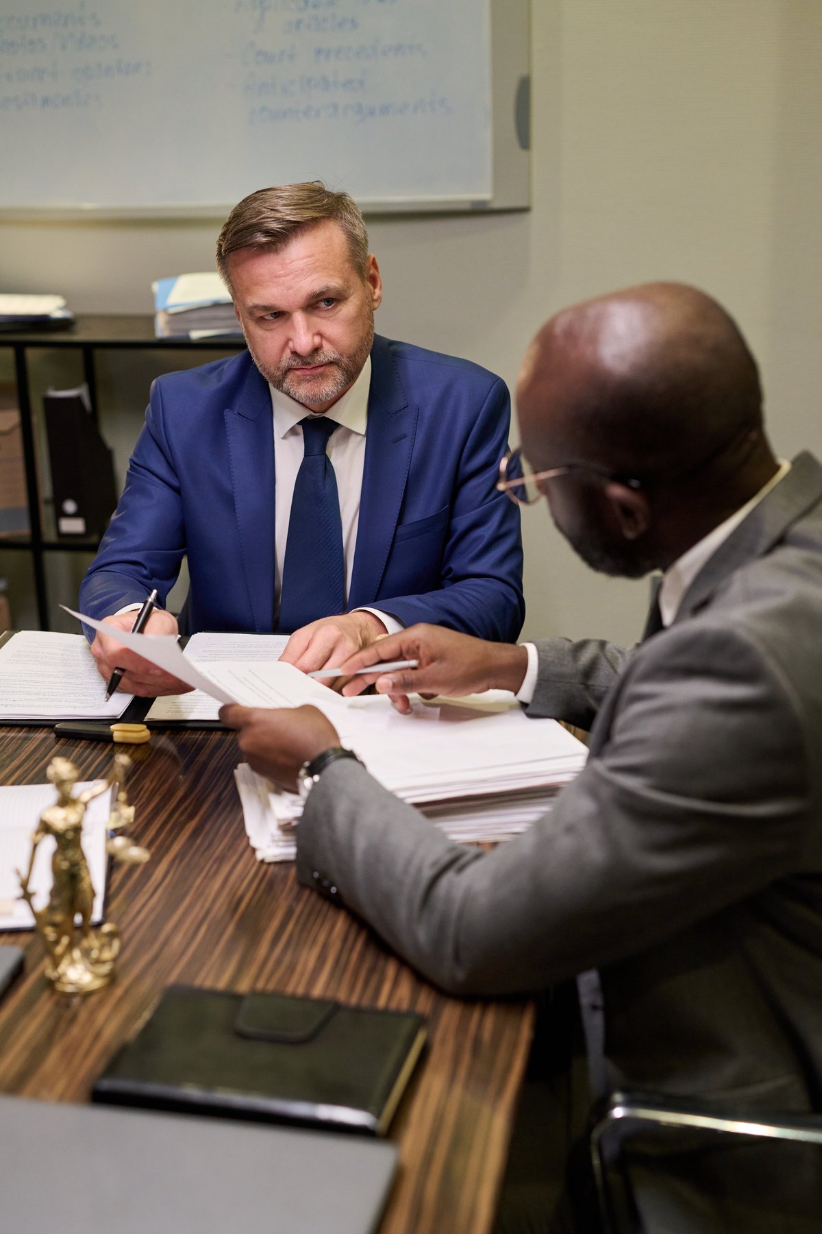 Professional listening attentively while explaining documents during business meeting at office table with legal paperwork, migration case review